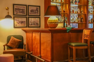 The polished bar counter and stools under pendant lights, spirits shelved behind.