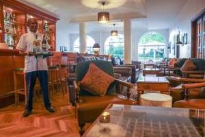 A barman carrying a tray through the panelled bar lounge.