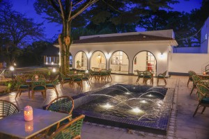 The illuminated fountain pool with the arcaded wing of the hotel lit behind it.