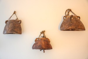 Three hanging cowbells against a plain white wall.