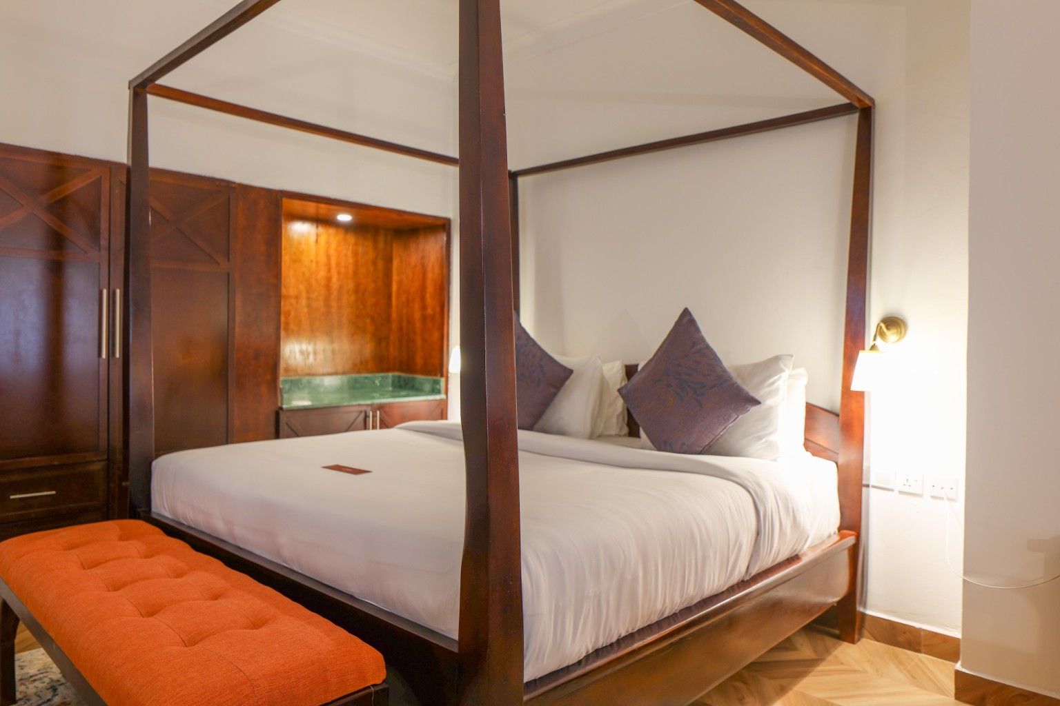 A four-poster king bed with an upholstered bench at its foot in an Executive Suite.