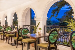 Tables laid on the arched veranda of Masaaba Restaurant, greenery through the arches.