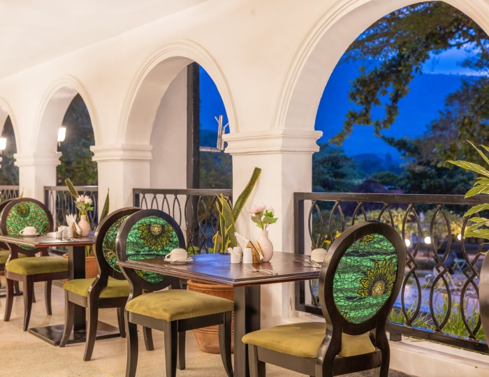Tables laid on the arched veranda of Masaaba Restaurant, greenery through the arches.