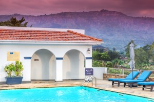 The arched poolside pavilion and loungers with hills on the horizon.