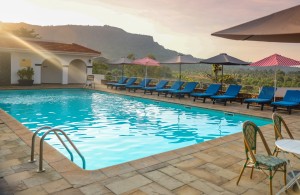 Blue sun loungers lined along the pool terrace with the escarpment behind.