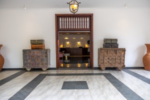 The reception desk framed by a timber doorway, painted chests either side.