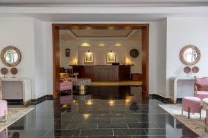 The polished reception hall with mirrors, console tables and the desk beyond.