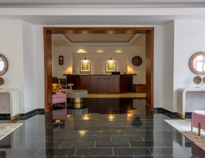 The polished reception hall, with mirrors, console tables and the desk beyond.