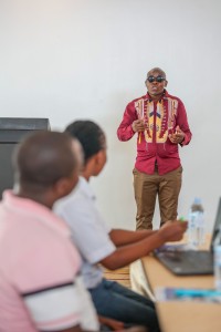 A facilitator addressing seated delegates in a meeting room.