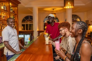 Guests with drinks at the bar counter, a barman serving.