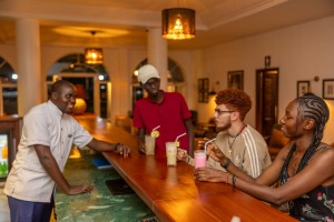 Guests with drinks at the bar counter, a barman serving.