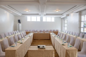 The conference hall dressed for a session, with covered chairs, notepads and water set out.