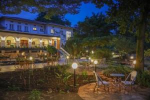 Candlelit tables and a lit water feature on the courtyard terrace at blue hour, the arcades glowing behind.