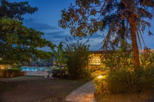 Candlelit tables and a lit water feature on the courtyard terrace at blue hour, the arcades glowing behind.