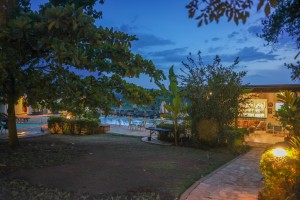 Candlelit tables and a lit water feature on the courtyard terrace at blue hour, the arcades glowing behind.