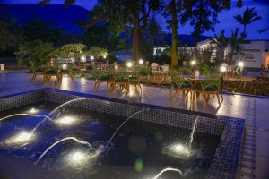 Candlelit tables and a lit water feature on the courtyard terrace at blue hour, the arcades glowing behind.