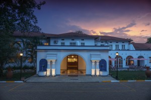 The symmetrical front elevation of the 1950s building at dusk, its central arch lit gold.