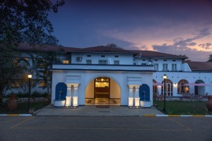 The symmetrical front elevation of the 1950s building at dusk, its central arch lit gold.