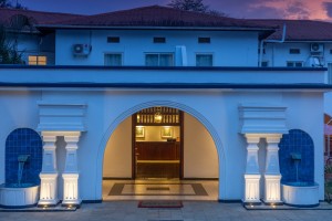 The symmetrical front elevation of the 1950s building at dusk, its central arch lit gold.