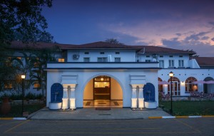 The symmetrical front elevation of the 1950s building at dusk, its central arch lit gold.
