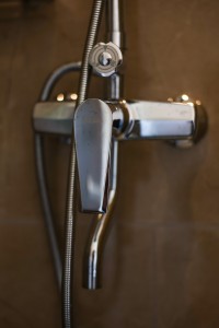 An en-suite bathroom with basin, mirror and a glazed shower, tiled in green marble.