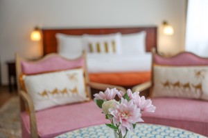 A guest room with king or twin beds, bedside lamps and curtained windows onto the garden.