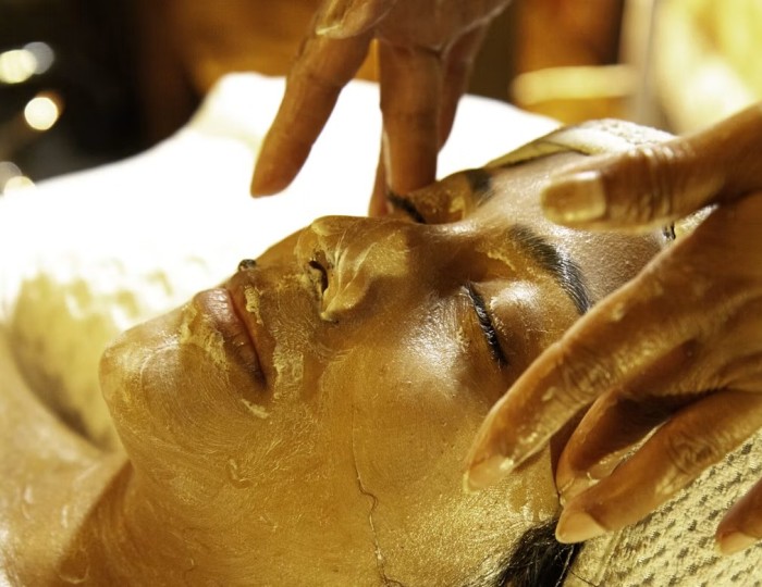 A therapist applies a facial treatment to a guest lying on a treatment bed at Kwetu Spa, lit warmly from the side.