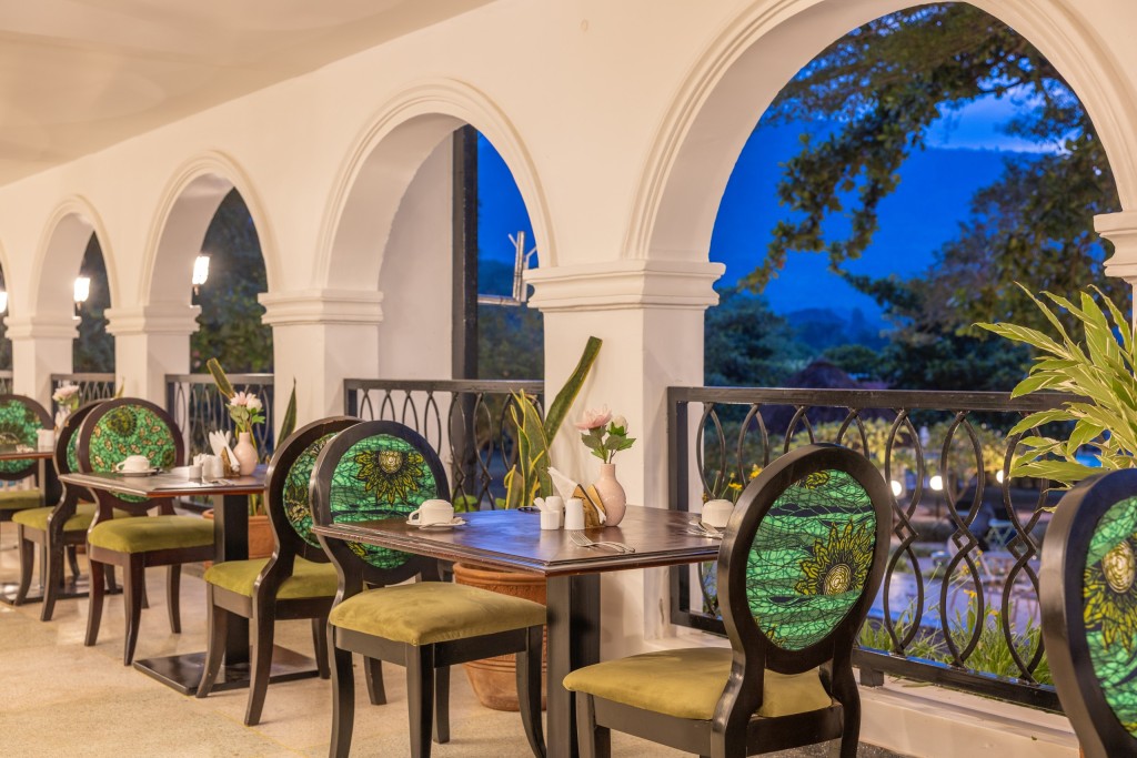 A table laid beside a tall arch in the dining room, the garden and trees showing through the opening.