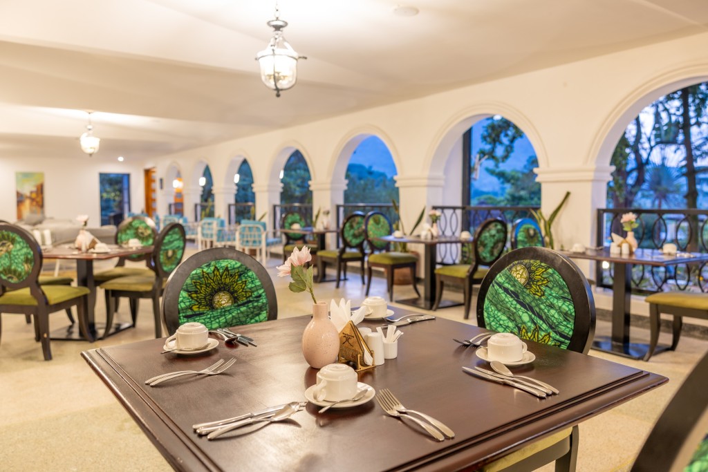 A laid table in the arcaded dining room, cane and timber chairs around it and the arches open to the garden.