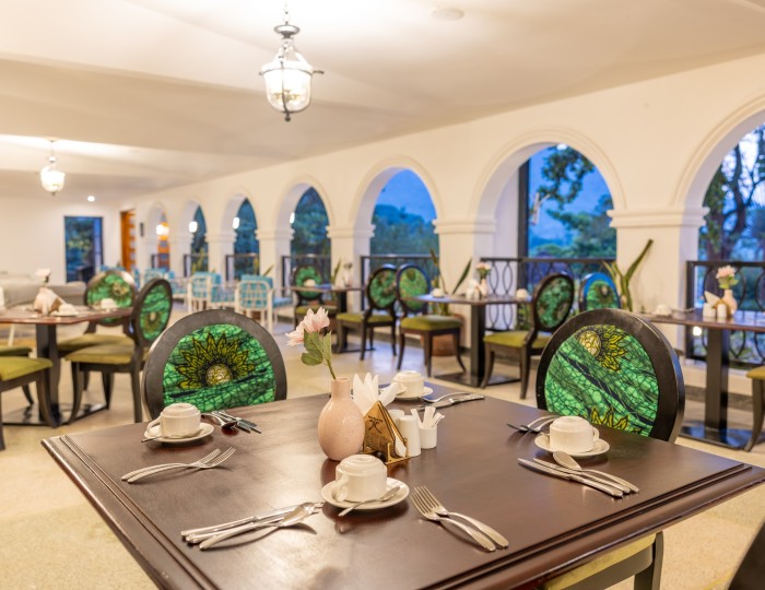 A restaurant table laid with cups, cutlery and side plates, the arched veranda running away behind it.