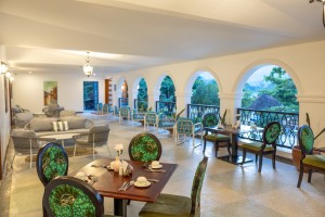 Masaaba Restaurant: tables and cane chairs along the arched veranda, hills and greenery through the openings.