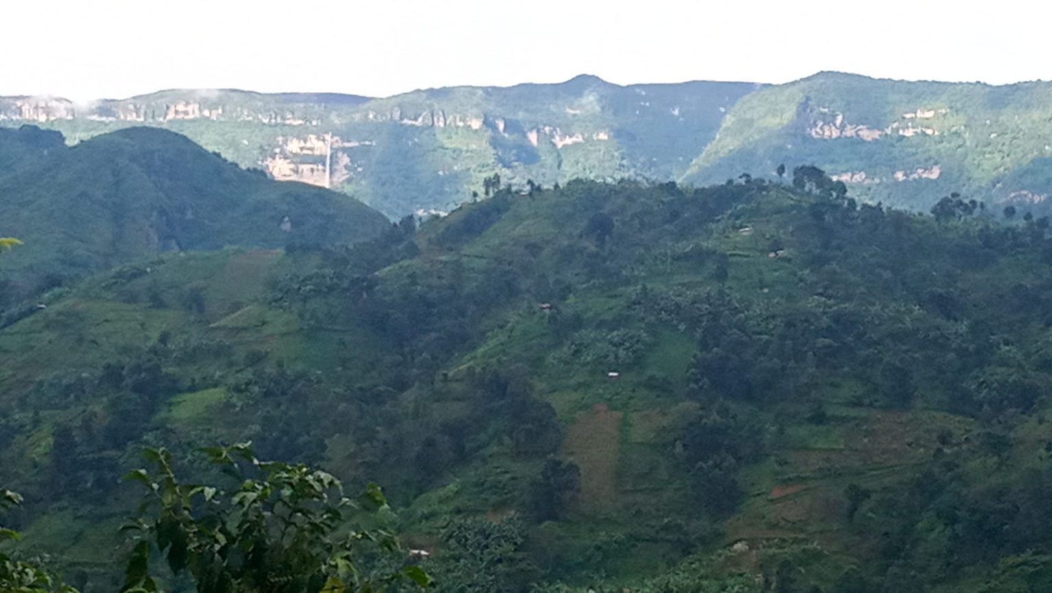 Hazy ridges and cliff lines of the Mount Elgon range above cultivated hills.