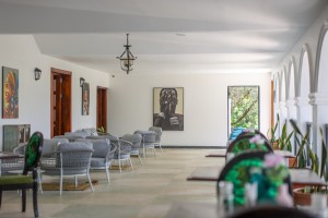 The dining room with its painted palm mural, teal napkins and carved timber furniture.