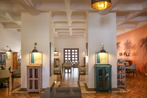 The dining room with its painted palm mural, teal napkins and carved timber furniture.