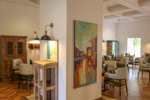 The dining room with its painted palm mural, teal napkins and carved timber furniture.