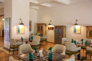 The dining room with its painted palm mural, teal napkins and carved timber furniture.