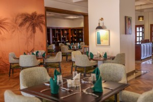 The dining room with its painted palm mural, teal napkins and carved timber furniture.