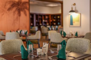 The dining room with its painted palm mural, teal napkins and carved timber furniture.