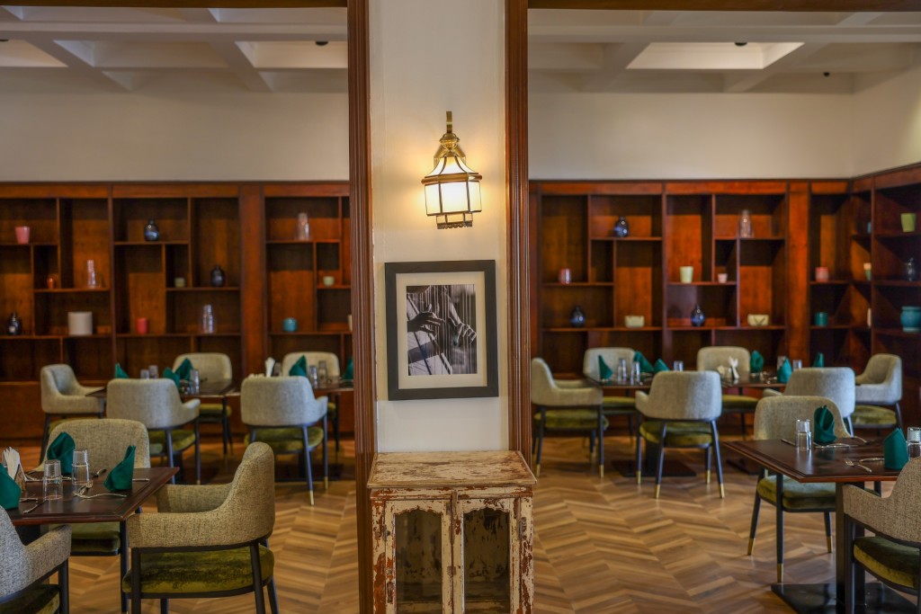 A quiet room lined with timber shelving, a lantern overhead and low armchairs drawn up to two small tables.