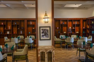 The dining room with its painted palm mural, teal napkins and carved timber furniture.