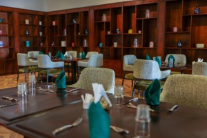 The dining room with its painted palm mural, teal napkins and carved timber furniture.