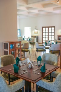 The dining room with its painted palm mural, teal napkins and carved timber furniture.