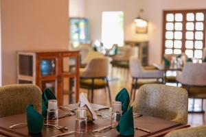 The dining room with its painted palm mural, teal napkins and carved timber furniture.