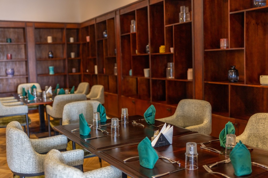 A long table laid with teal napkins in a timber-shelved room, upholstered armchairs down both sides.