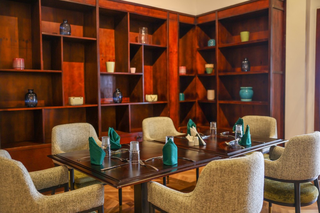 A table laid with green napkins in a room lined floor to ceiling with timber shelving.
