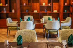 A wood-panelled dining room with upholstered chairs and tables laid for service.