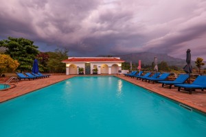 The lit pool and pavilion at dusk, with garden furniture on the terrace.