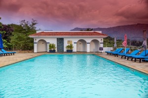 The outdoor pool and its arched pavilion under a sunset sky, blue loungers along the terrace.