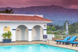 The outdoor pool and its arched pavilion under a sunset sky, blue loungers along the terrace.