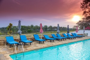 The outdoor pool and its arched pavilion under a sunset sky, blue loungers along the terrace.